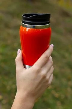 Put your hand on a bright orange thermos mug Stock Photos