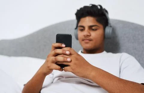 Put your musical knowledge to the test. a young man using his cellphone while Stock Photos