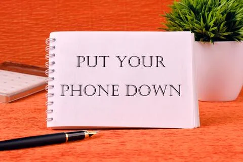 Put your phone down text written on a white notebook on an orange background Stock Photos