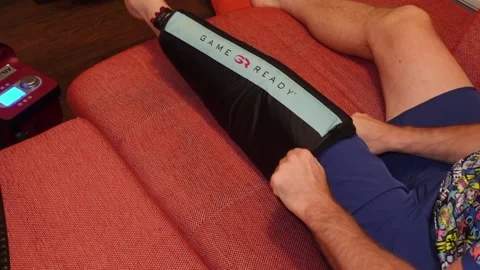 Puting on Game Ready machine knee bandage Stockbeeldmateriaal 166574097