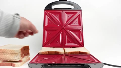 Puts bread into an electric sandwich maker to make sandwiches. Electric sandwich Stock Footage 301676130