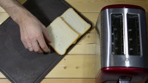 Puts bread for a toast on a table board. Toaster on the table Stock Footage 122123254