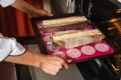 Puts cakes in the oven Stock Photos