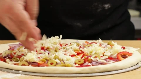 Puts cheese on the pizza dough. Stock Footage 160968449