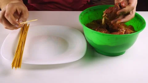 Puts hand raw meat on bamboo skewers.Shashlik marinated in a green bowl. Stock-Footage 130666505