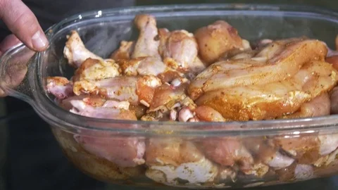 Puts marinated chicken on glass table to grill them Stock Footage 121364223