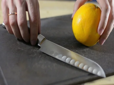 Puts an orange and a knife on a black cutting board Stock Footage 121665149