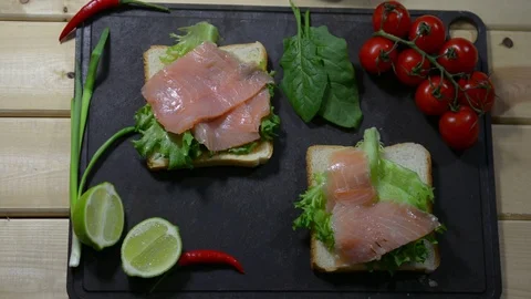 Puts pieces of fresh red fish on lettuce. Two toasts and spinach leaves. 스톡 동영상 122490485