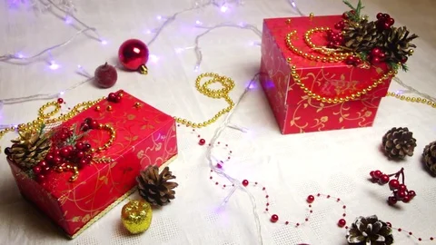 Puts red hand-made gift boxes and Christmas decorations, golden apples and bumps Stock Footage 82406659