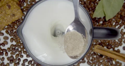 Puts a spoonful of brown, cane sugar in milk foam in a cappuccino machine. Stock Footage 165675177