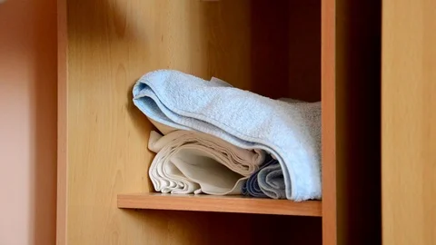 Puts things clothes in a closet on a shelf, multi-colored t-shirts, wardrobe 库存影片 125229818