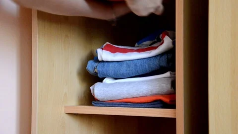 Puts things clothes in a closet on a shelf, multi-colored t-shirts, wardrobe Vidéo 125229819
