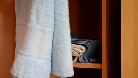 Puts things clothes in a closet on a shelf, multi-colored t-shirts, wardrobe Stockbeeldmateriaal 125229846