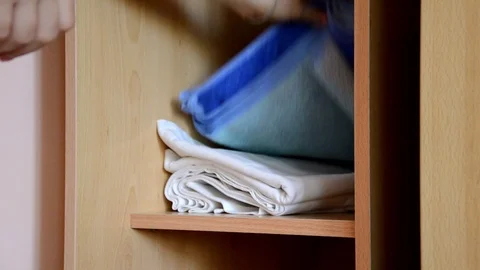 Puts things clothes in a closet on a shelf, multi-colored t-shirts, wardrobe 库存影片 125229850