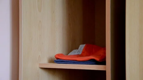 Puts things clothes in a closet on a shelf, multi-colored t-shirts, wardrobe 库存影片 125229882