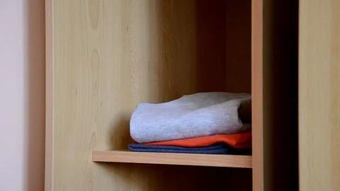 Puts things clothes in a closet on a shelf, multi-colored t-shirts, wardrobe 库存影片 125229886