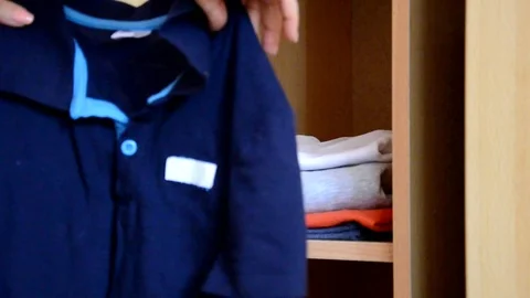 Puts things clothes in a closet on a shelf, multi-colored t-shirts, wardrobe 库存影片 125229901