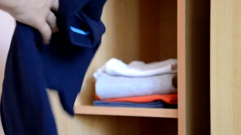 Puts things clothes in a closet on a shelf, multi-colored t-shirts, wardrobe Vidéo 125229911
