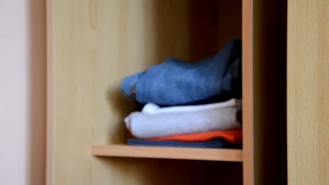 Puts things clothes in a closet on a shelf, multi-colored t-shirts, wardrobe Stockbeeldmateriaal 125229918