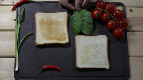Puts two sheets of spinach on a chopping board next to two toasts. Chilli Stock Footage 122491087