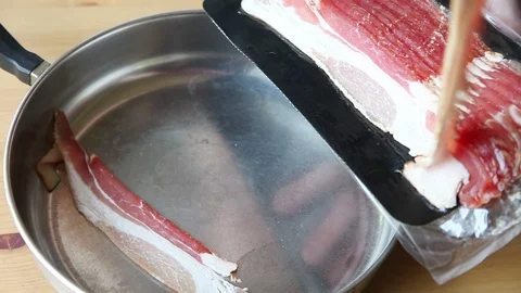 Putting bacon in a frying pan Stock Footage 89347219