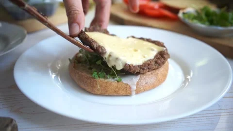 Putting beef cutlet on a cheeseburger with whole grain buns and microgreens clos Stock Footage 132317636