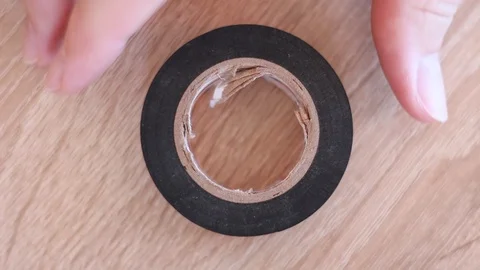 Putting boobin of insulating tape on table and taking it back Stock Footage 101676965