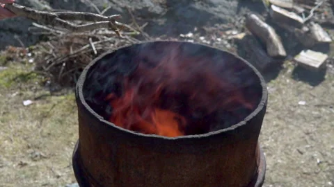 Putting a branch in burning fire barrel. Springtime outdoor cleaning. Vídeos de archivo 196501415