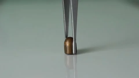 Putting a bullet on a table with tweezers Vídeo Stock 66755577