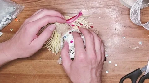 Putting Button Eyes on a Handmade Yarn Doll Stock Footage 287230286