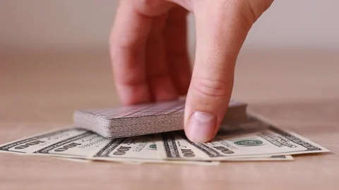 Putting card deck over dollar banknotes Stock Footage 93336640