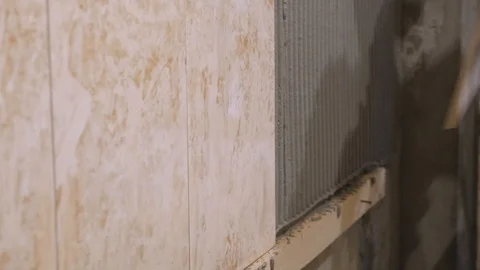 Putting ceramic tile on the wall. Ceramist is slowly laying ceramic tile on Stock Footage 87542796