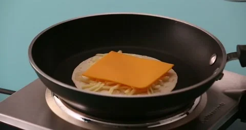 Putting chicken on a slice of cheese, shredded cheese, and a tortilla 2 Stock Footage 132203811