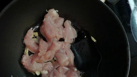 Putting chicken into wok overhead Stock Footage 98360844