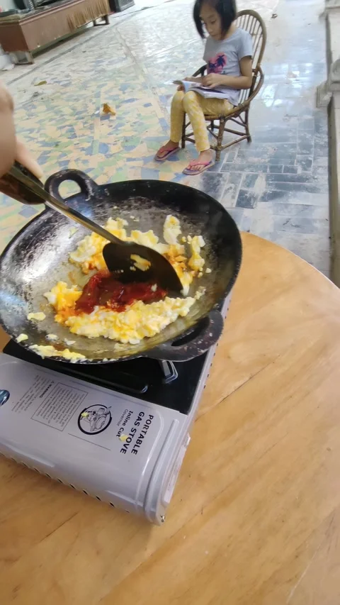 Putting chili paste into scrambled eggs, cooking on a propane gas stove Stock Footage 331497182