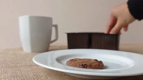 Putting the chocolate biscuit on the box into the white plate Stock Footage 150398730