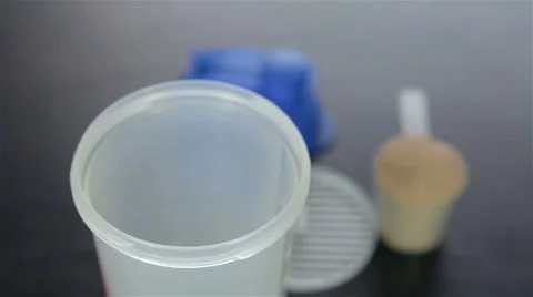 Putting  chocolate whey isolate protein into plastic white shaker Stock Footage 35587134