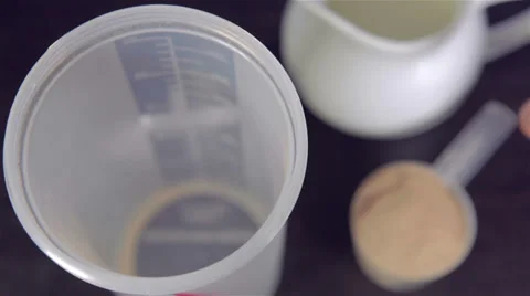 Putting  chocolate whey isolate protein into plastic white shaker Stock Footage 35587259