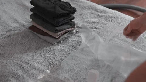 Putting clothes into vacuum bag for storage. Wardrobe storage concept. Stock Footage 305313077