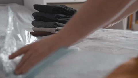 Putting clothes into vacuum bag for storage. Wardrobe storage concept. Stock Footage 305313176