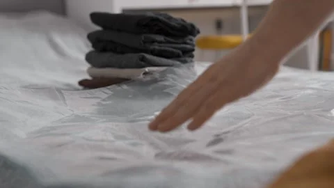 Putting clothes into vacuum bag for storage. Wardrobe storage concept. Stock Footage 305313222