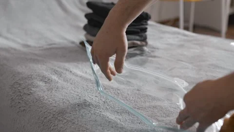 Putting clothes into vacuum bag for storage. Wardrobe storage concept. Stock Footage 305313252
