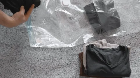 Putting clothes into vacuum bag for storage. Wardrobe storage concept. Stock Footage 305313475
