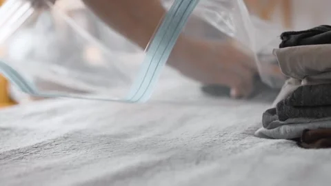 Putting clothes into vacuum bag for storage. Wardrobe storage concept. Stock Footage 305313535