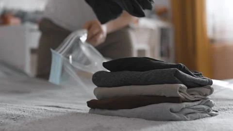 Putting clothes into vacuum bag for storage. Wardrobe storage concept. Stock Footage 305313584