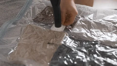 Putting clothes into vacuum bag for storage. Wardrobe storage concept. Stock Footage 305313645