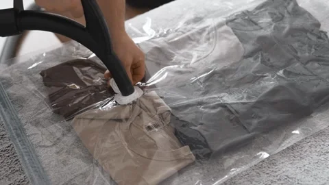 Putting clothes into vacuum bag for storage. Wardrobe storage concept. Stock Footage 305313847