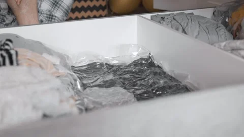 Putting clothes in vacuum bag into under the bed storage. Wardrobe storage conce Stock Footage 305313979