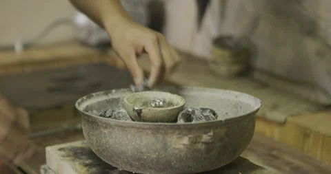 Putting coal to melt silver in table top clay bowl Stock Footage 141369551