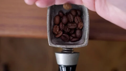 Putting coffee beans into the hand coffee grinder Stock-Footage 128949526